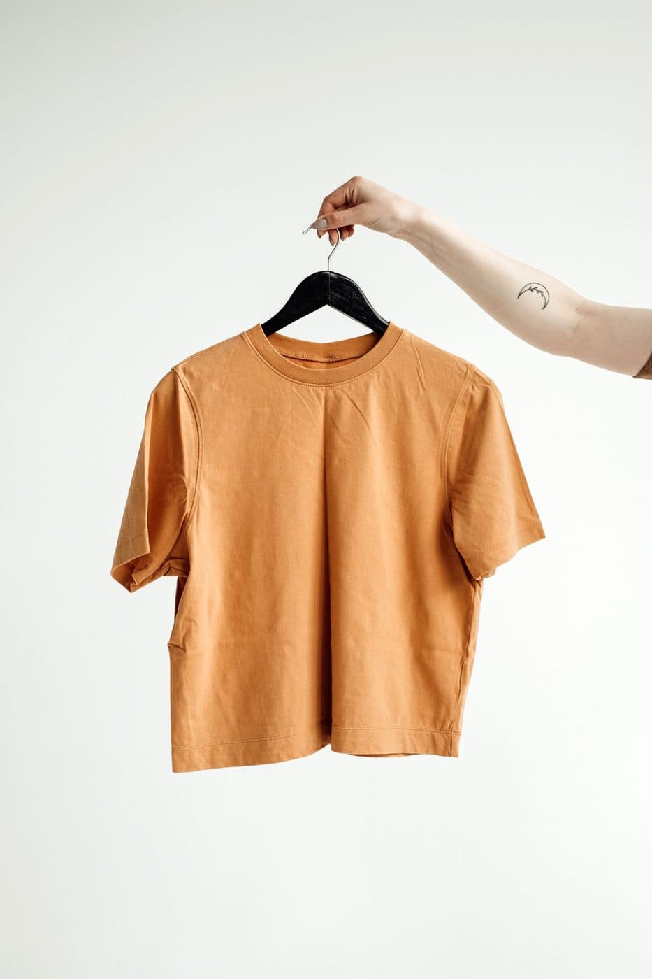 Orange t-shirt held up on a black hanger